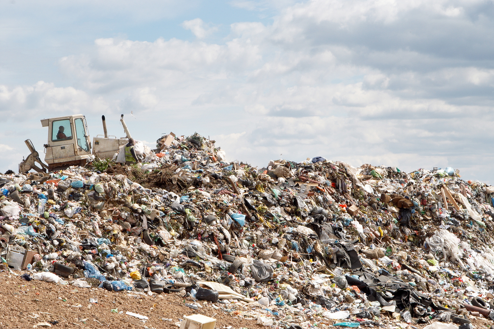 Digger working on large landfill highlighting importance of recycling